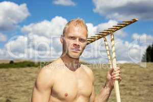 Man in meadow with wooden rake