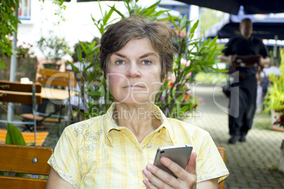Woman with smartphone sitting in the beer garden