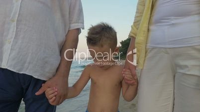 Child with grandparents walking on the shore