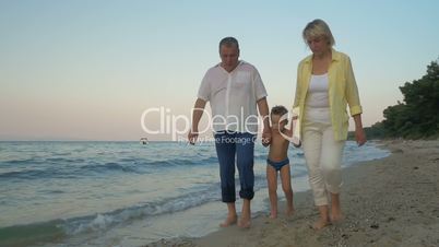 Grandparents and grandchild walking on the beach