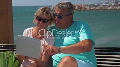 Senior couple using touch pad on waterfront