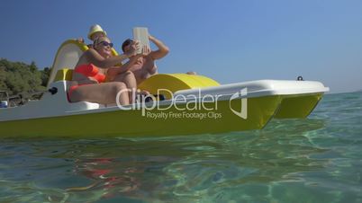 Family in pedal boat taking selfie with pad