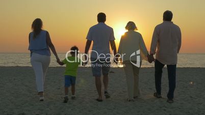 Family looking at golden sunset over the sea