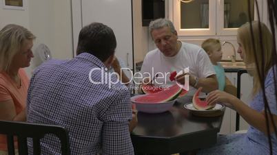 Big family eating watermelon in the kitchen