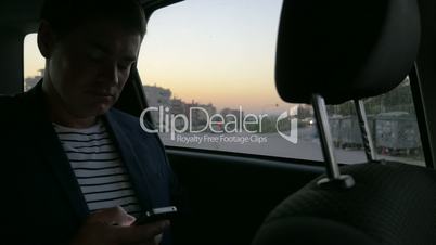 Man in car browsing the internet on smart phone