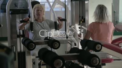 Senior women training on exercisers in the gym