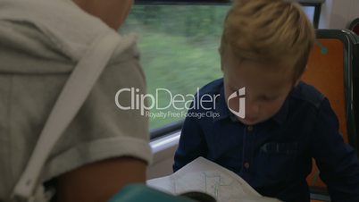 Boy with mom looking at map in train