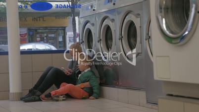 Mother and child using mobile in the laundry