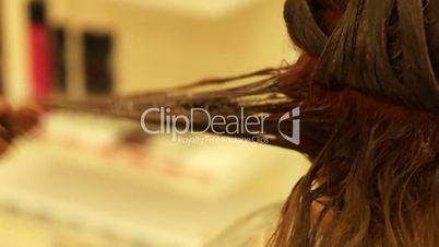 hairdresser holding a lock of hair and coloring hair in a beauty salon