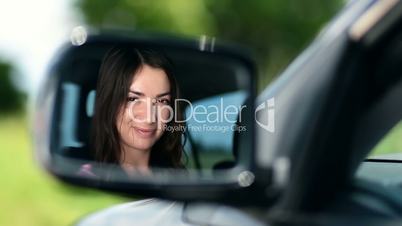 Reflection of pretty woman in car side-view mirror