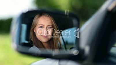 Young woman driver looking at car side view mirror