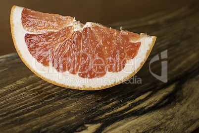 Slice of Red Juicy Grapefruit on Vintage Wooden Board