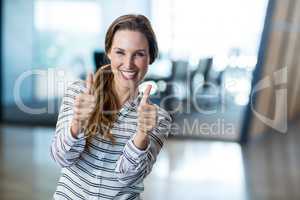 Woman showing thumbs up in office