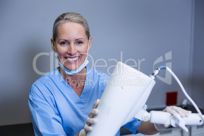 Smiling dental assistant adjusting light in clinic