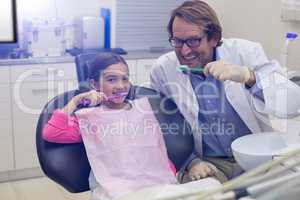 Smiling dentist and patient brushing their teeth