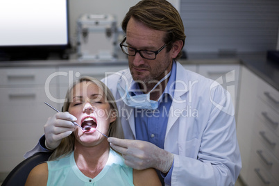 Dentist examining a woman with tools