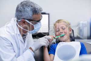 Dentist brushing a young patients teeth