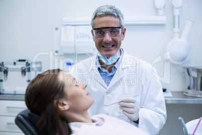 Smiling Dentist examining a patient with tools