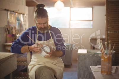 Male potter painting on bowl