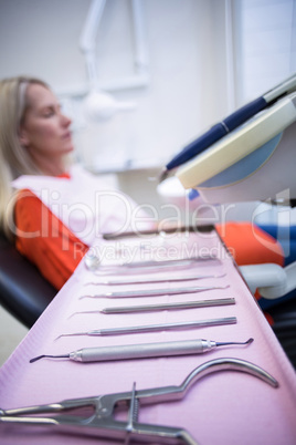 Woman relaxing on dentist chair with dental tools on foreground