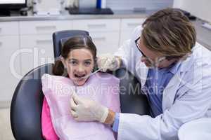 Dentist examining a young patient with tools