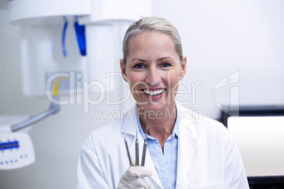 Portrait of female dentist holding dental tools