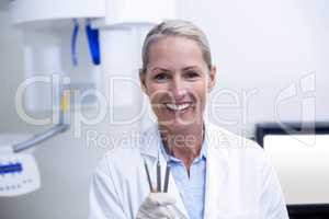 Portrait of female dentist holding dental tools