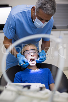 Dentist examining a young patient with tools