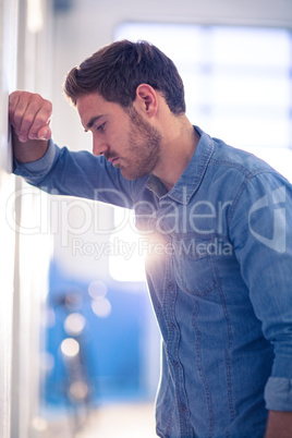 Tired businessman leaning on wall