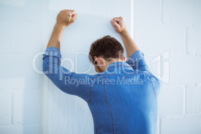 Tired businessman leaning on wall