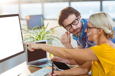 Graphic designers interacting while working on computer
