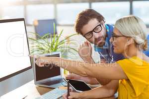 Graphic designers interacting while working on computer