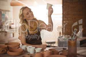 Beautiful female potter checking pot