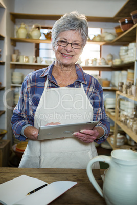 Happy female potter using digital tablet