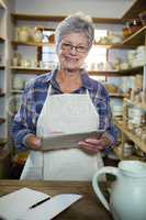 Happy female potter using digital tablet