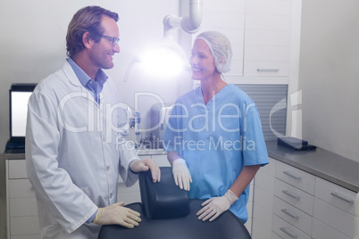 Smiling dentist talking to dental assistant