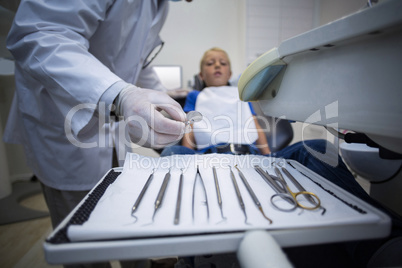 Dentist picking up dental tools to examine a young patient