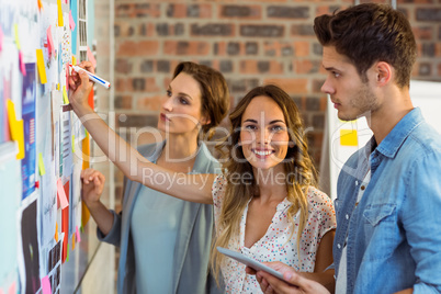 Business executive writing on sticky notes on whiteboard