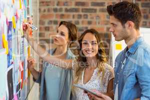 Business executive writing on sticky notes on whiteboard