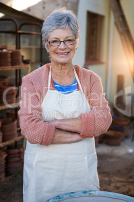 Happy female potter standing in pottery workshop