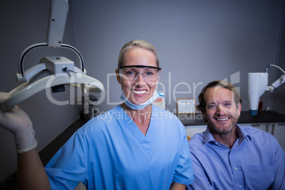 Smiling dental assistant adjusting light in clinic