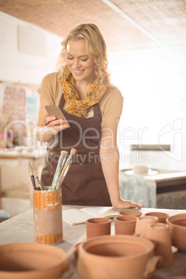 Female potter using mobile phone while working