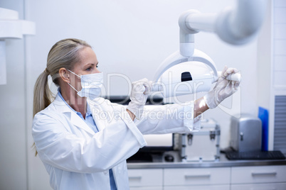 Female dentist adjusting dental lights