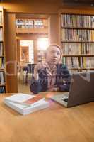 Thoughtful young woman using laptop in library