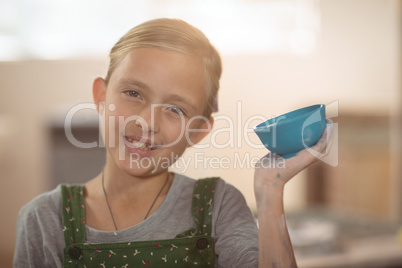 Portrait of girl showing bowl in pottery workshop