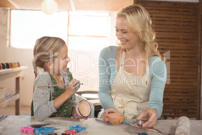 Female potter assisting girl in painting