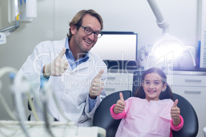 Smiling dentist and young patient showing thumbs up