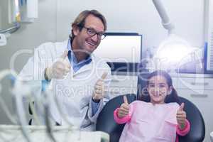 Smiling dentist and young patient showing thumbs up