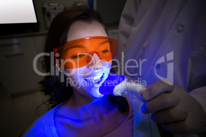 Dentist examining a female patient with dental tool