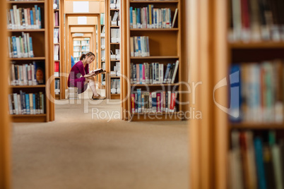 Young woman reading book in library